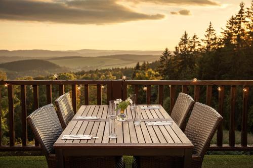 a wooden table with chairs on a balcony with a view at Hotel Zámeček Janovičky in Broumov