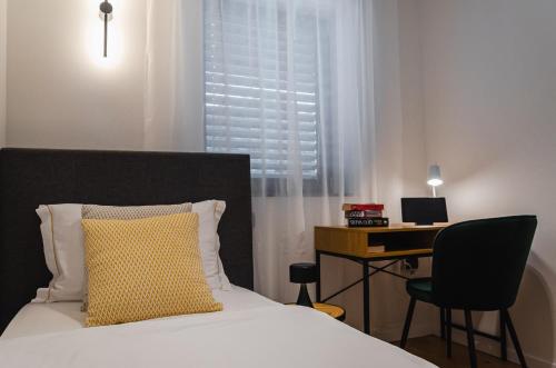 a bed with a yellow pillow and a desk in a room at Apartma Vila Center LUX in Slovenj Gradec