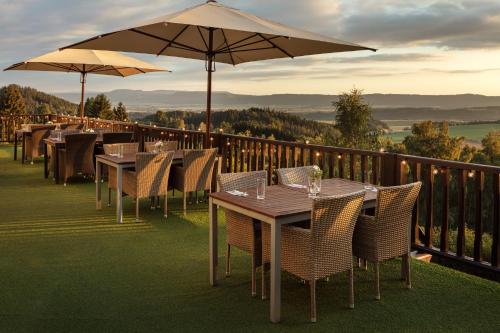 una fila de mesas y sillas con sombrillas en el balcón en Hotel Zámeček Janovičky, en Broumov