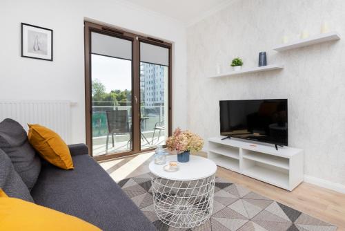 a living room with a couch and a tv at Modern Apartment with Balcony by Renters in Gdańsk
