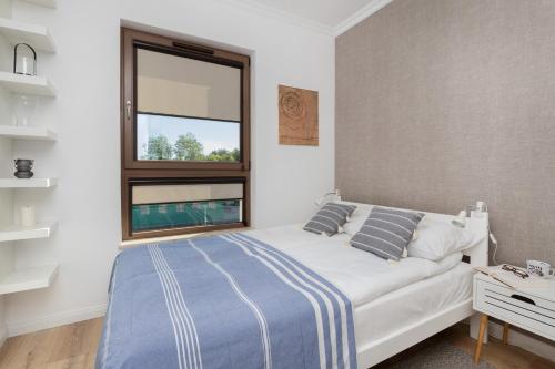 a bedroom with a white bed and a window at Modern Apartment with Balcony by Renters in Gdańsk