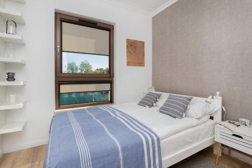 a bedroom with a white bed and a window at Modern Apartment with Balcony by Noclegi Renters in Gdańsk