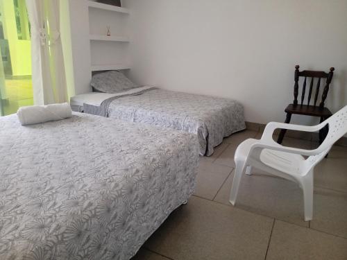 a bedroom with two beds and a white chair at Casa campestre californiana con piscina privada in El Brasil