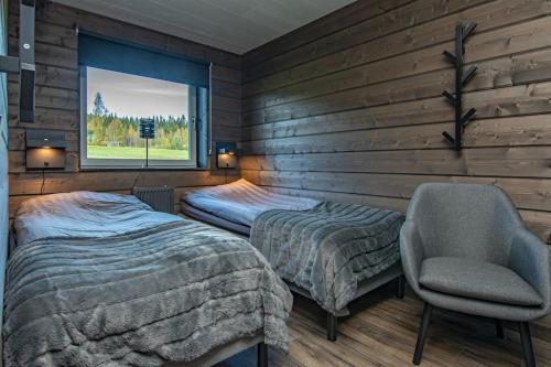 a bedroom with two beds and a chair and a window at Villa Black in Slussfors