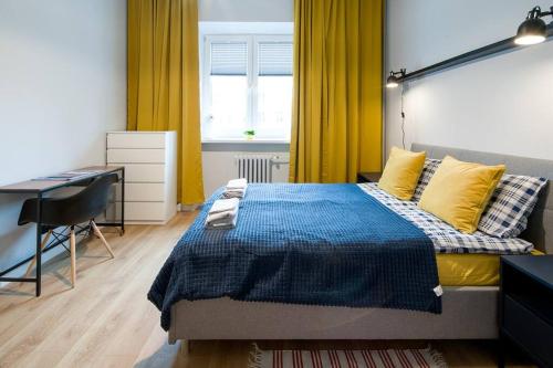 1 dormitorio con 1 cama con escritorio y cortinas amarillas en Nowa Huta Super Star en Cracovia