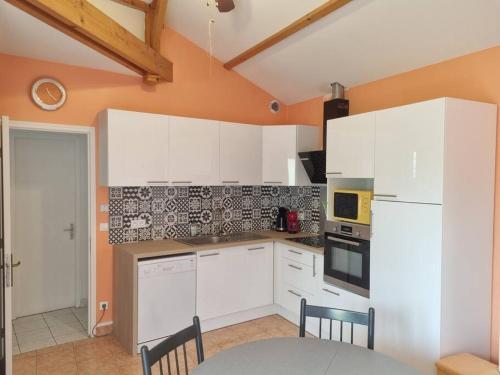 una cocina con armarios blancos y una mesa con sillas. en Maison centre Jard et à 8min à pied de la plage, en Jard-sur-Mer