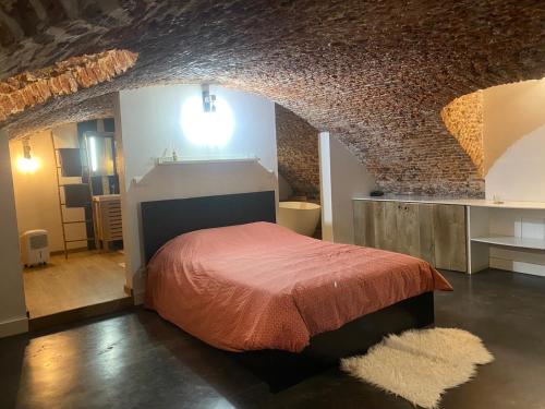 um quarto com uma cama num quarto com uma parede de tijolos em Au Beau Lieu de Metz em Lille