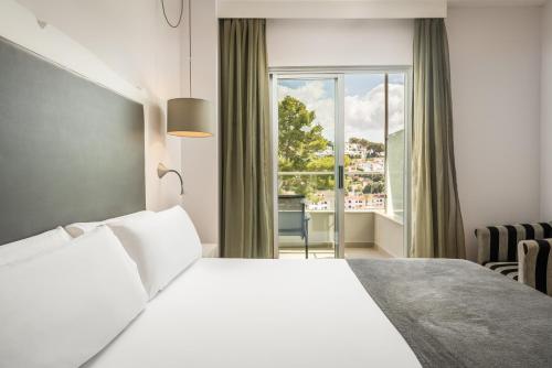 a bedroom with a white bed and a window at ARTIEM Audax - Adults Only in Cala Galdana