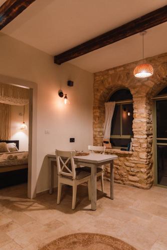 a room with a table and chairs and a bed at אבן על הנחל in Merhav Am