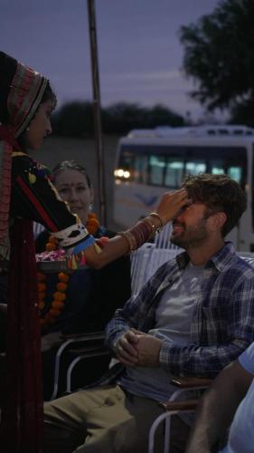 a woman is washing the eyes of a man at Bikaner Desert Camp and Resort in Bikaner
