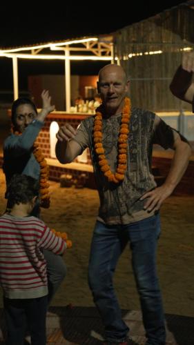 a man wearing an orange necklace standing next to a child at Bikaner Desert Camp and Resort in Bikaner