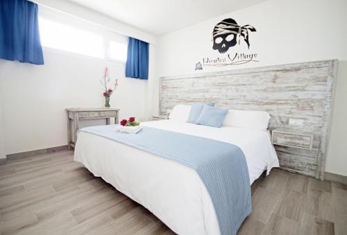 una camera da letto con un grande letto bianco con testiera in legno di Gran Santa Ponsa Apartments a Santa Ponsa