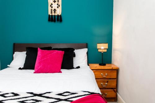 a bed with a pink pillow and a blue wall at Saltwell Oasis: 5-Bed Delight in Low Team