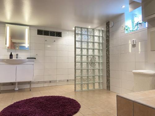 uma casa de banho com um lavatório e um chuveiro com um tapete roxo em Holiday apartment in Vessigebro em Vessigebro