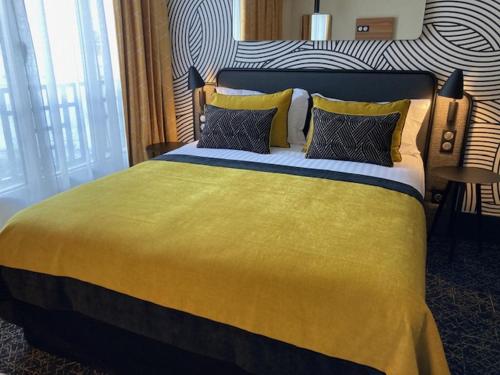 a bedroom with a large yellow bed with two pillows at Hotel Vacances Bleues Villa Modigliani in Paris
