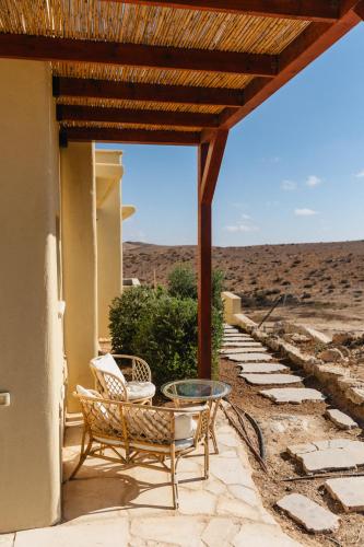 a patio with a table and chairs and a view of the desert at אבן על הנחל in Merhav Am