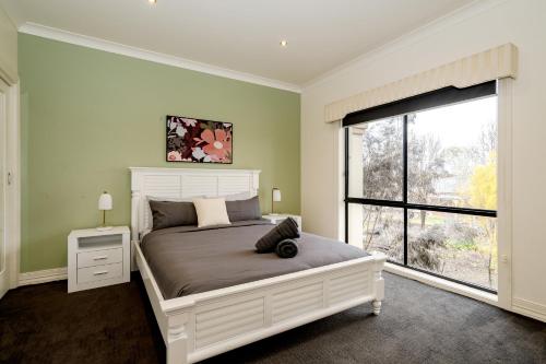 1 dormitorio con cama grande y ventana grande en A Touch of Red - Spa, Theatre, Sleeps 6! en Waurn Ponds