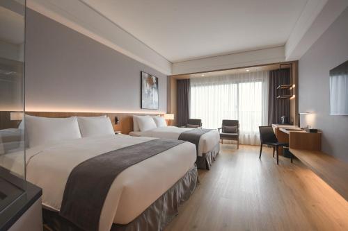 a hotel room with two beds and a desk at Grand Banyan Hotel in Tainan