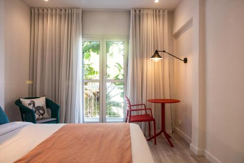 a bedroom with a bed and a table and a window at Dodo Square in Grand-Baie
