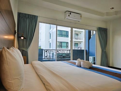 a bedroom with a large bed with a large window at The Base Inn Pattaya in Pattaya Central