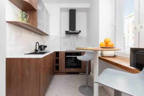 a kitchen with wooden cabinets and a table with oranges on it at Apartment with Balcony Gdynia Downtown by Renters in Gdynia