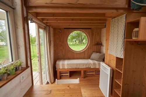 una piccola camera da letto in una piccola casa con finestra di Tiny house near the Mont-Saint-Michel a Ducey