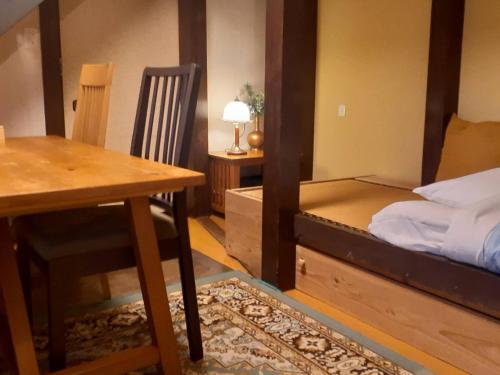 Cette chambre comprend un lit, une table et un bureau. dans l'établissement HAKUBA IKEDA LIFE KAN APARTMENTS, à Hakuba