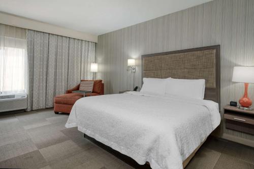 una camera d'albergo con un grande letto e una sedia di Hampton Inn St. Louis/Collinsville a Collinsville