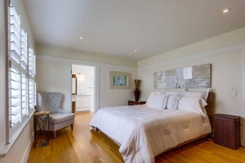 a bedroom with a large white bed and a chair at Cozy Craftsman Bungalow, Hillcrest/Mission Hills in San Diego