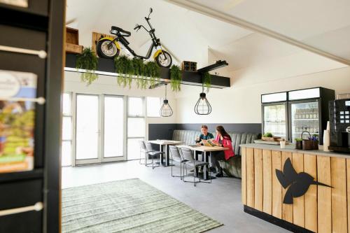two people sitting at tables in a room with a kitchen at Goudvink 547 De IJsvogel Veluwe Voorthuizen in Voorthuizen