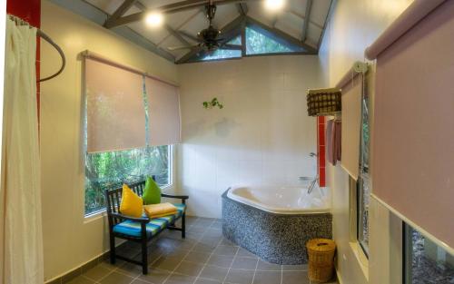 ein Badezimmer mit einer Badewanne, einem Waschbecken und einem Stuhl in der Unterkunft Sutera Sanctuary Lodges At Manukan Island in Kota Kinabalu