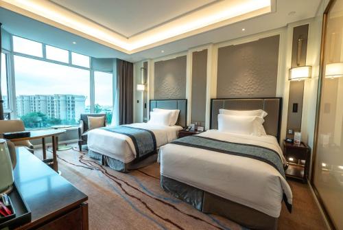 a hotel room with two beds and a desk at Wyndham Qingdao l Free Fixed-Time Shuttle Service Between Hotel and Airport & North Railway Station l Outdoor Children's Amusement Park l 1-Hour Play Snooker or Table Tennis in Qingdao