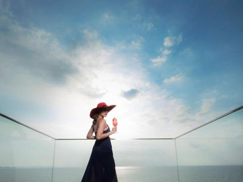 a woman in a hat holding an ice cream against the sky at Veranda Resort Pattaya - MGallery by Sofitel in Jomtien Beach