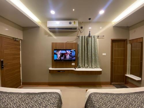 sypialnia z dwoma łóżkami i telewizorem na ścianie w obiekcie Hotel Sivas Regency w mieście Theni