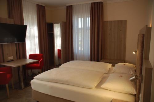 1 dormitorio con 1 cama con sábanas blancas y mesa en Aparthotel Weißenhorn en Weißenhorn