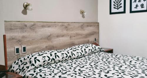 a bedroom with a bed with a black and white comforter at Hotel Los Sauces in Cafayate