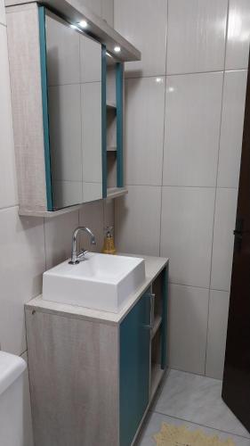 een badkamer met een wastafel en een spiegel bij Muito aconchegante perto do centro e da praia in Capão da Canoa