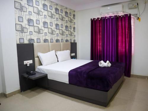 a bedroom with a bed with a purple comforter at Libra Cottage in Port Blair