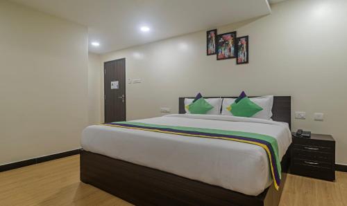 Un dormitorio con una cama grande con almohadas verdes. en Treebo Address Inn Jubilee Hills, en Hyderabad