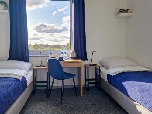 a room with two beds and a desk with a window at Mile Gdansk Airport & Parking Długoterminowy in Gdańsk
