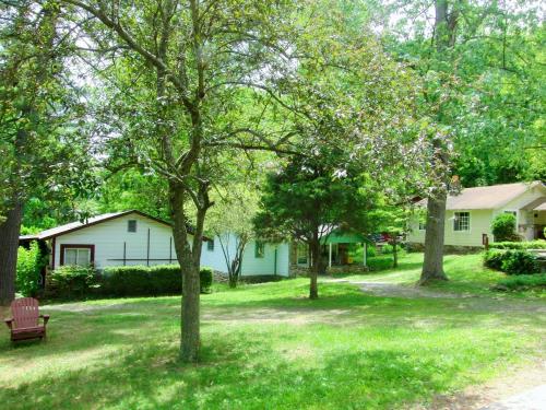 a yard with a house and a bench and trees at The Pines Cottages in Asheville