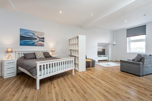 a bedroom with a bed and a couch and a chair at Walled City Apartments in Derry Londonderry