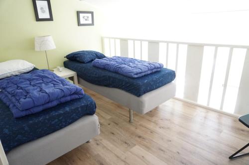 2 letti con coperte blu in una camera con pavimenti in legno di Kustverhuur, Oude manege Nieuwvliet, Nieuwvliet 3 - 9 a Nieuwvliet