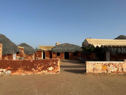 a group of buildings with thatched roofs in a field at Jaisalmer Safari Base & Camp in Khuri