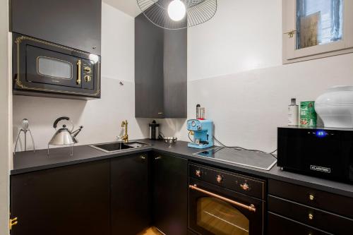 une cuisine avec un évier et un micro-ondes dans l'établissement Le Musée - Appartement prestigieux & chic, à Montpellier