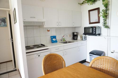 a kitchen with white cabinets and a table and chairs at Kustverhuur, Oude manege Nieuwvliet, Nieuwvliet 11 in Nieuwvliet