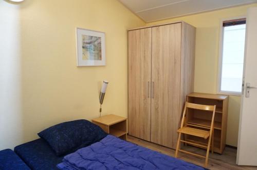 a bedroom with a blue bed and a wooden cabinet at Kustverhuur, Oude manege Nieuwvliet, Nieuwvliet 11 in Nieuwvliet