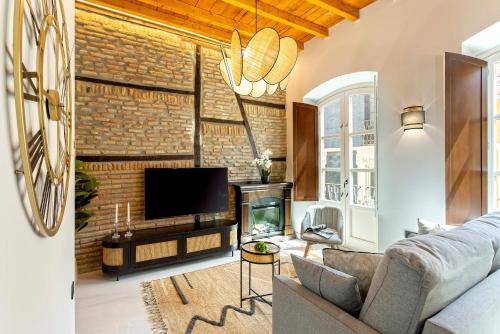 a living room with a couch and a tv and a brick wall at Genteel Home Catedral Granada in Granada
