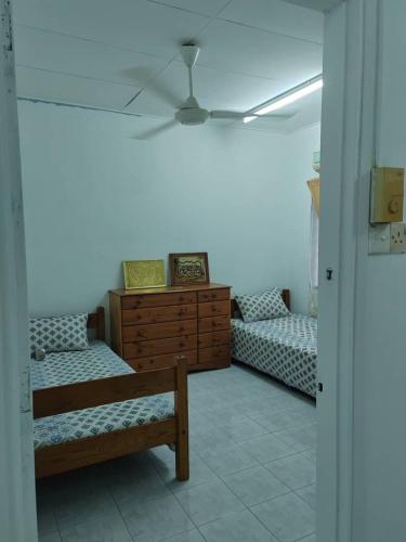 De' Aman Homestay في جيترا: غرفة بسريرين وخزانة خشبية