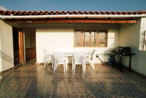 a patio with white chairs and a table and a piano at Maison familiale à Tarrafal. in Tarrafal